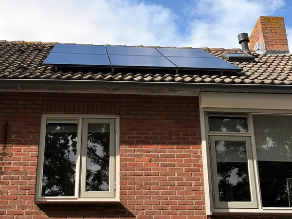 Bakstenen woning met zes zwarte zonnepanelen op het pannendak