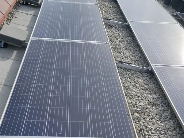 Twee lange rijen zonnepanelen op een plat dak met grind
