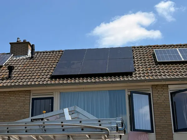 Rijwoning met zes zwarte zonnepanelen op het pannendak