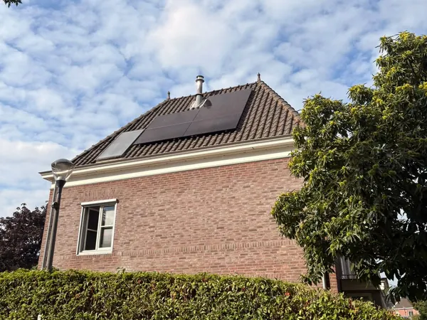 Vrijstaande bakstenen woning met zwarte zonnepanelen op het schilddak