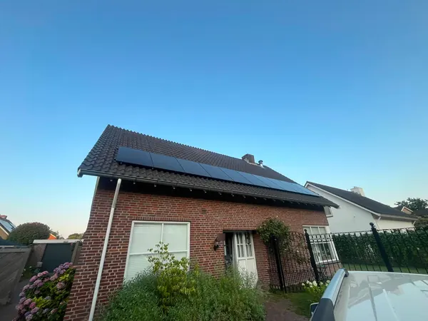 Vrijstaande bakstenen woning met een lange rij zwarte zonnepanelen op het dak
