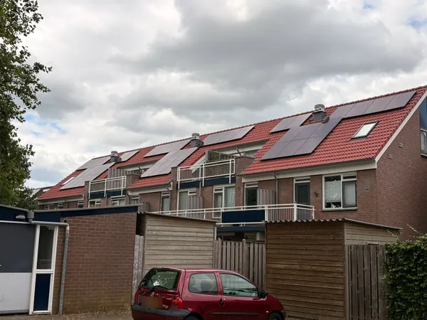 Woonblok met zwarte zonnepanelen op rode pannendaken